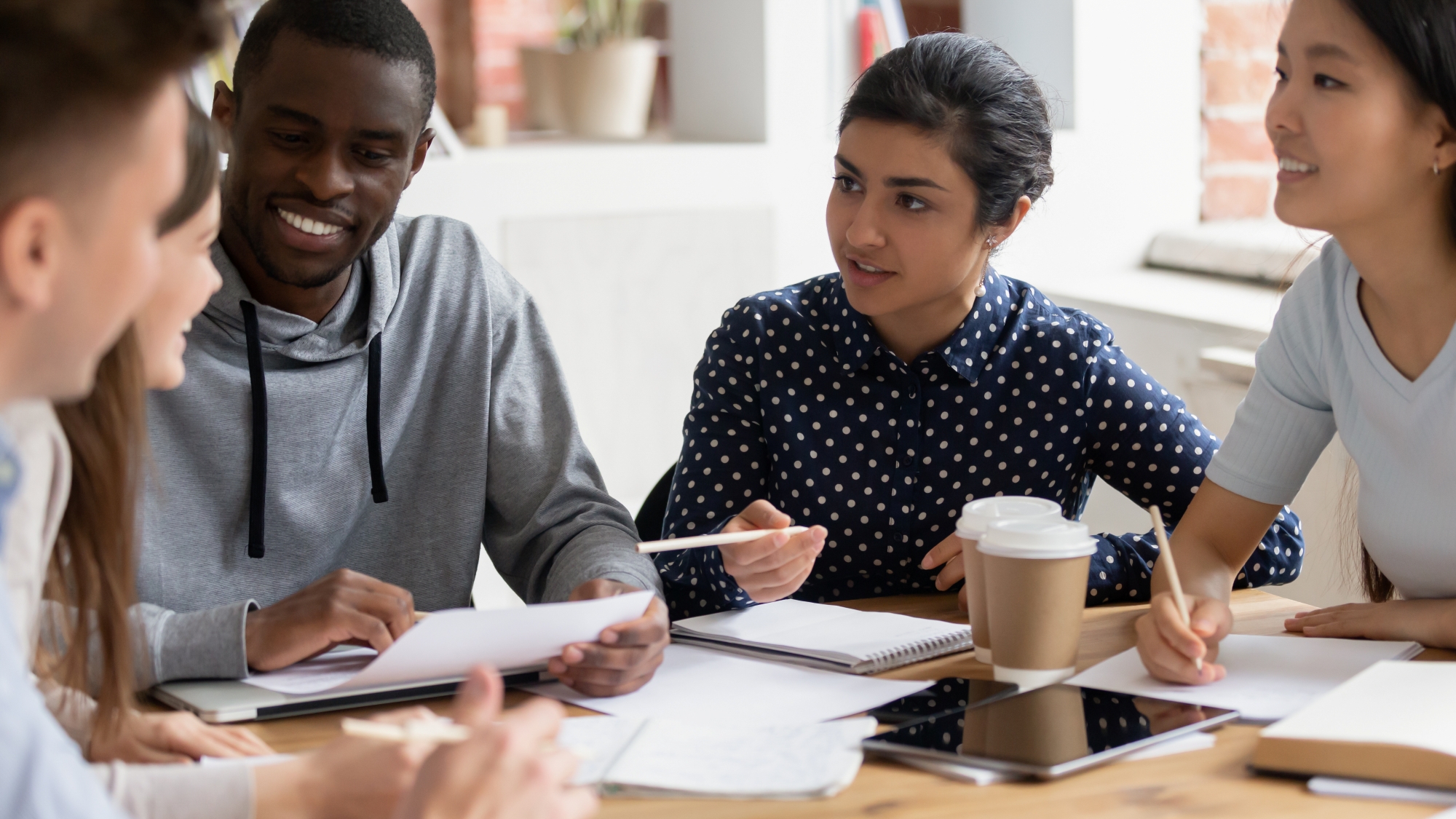 A group of young people sitting around a table having a meeting.