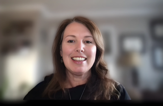 A woman smiling while in front of a blurred background..
